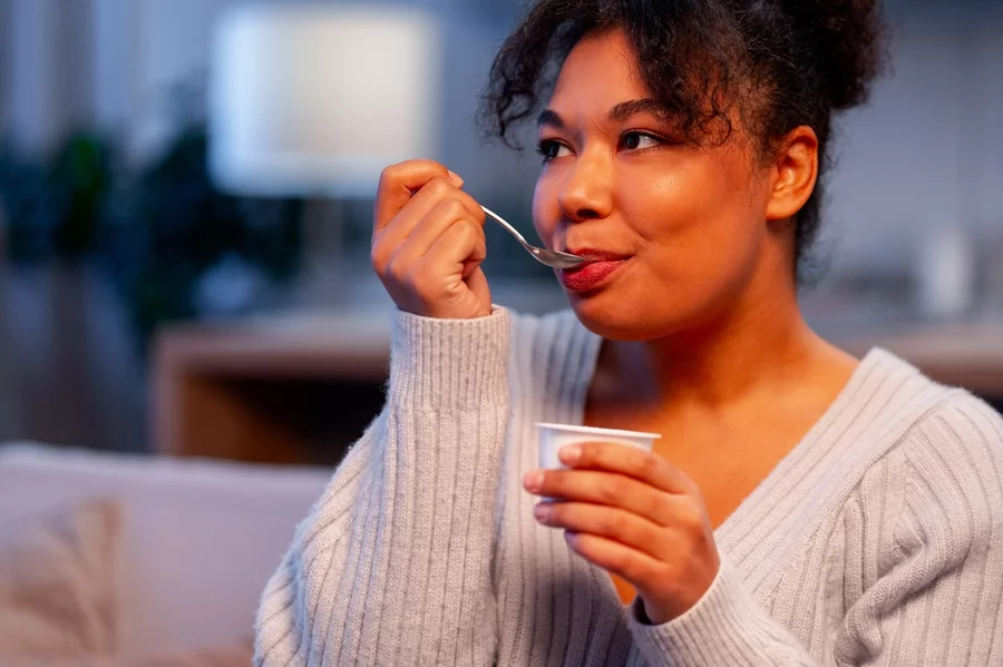 Young woman eating plain yogurt