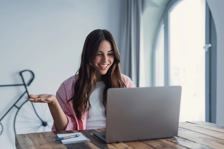 A cheerful young woman uses a laptop