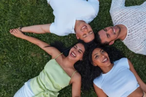Group of diverse friends lying in a circle on green grass