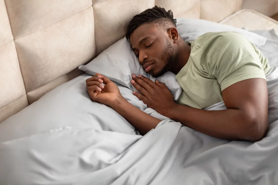 Young adult male sleeping comfortably in bed