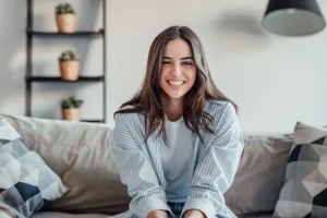 Smiling girl with pointed jawline sitting on a couch